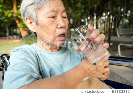 Asian senior woman holding glass of water,hands shaking while drinking water,elderly with hands tremor uncontrolled body tremors,symptom of essential tremor,parkinson's disease,neurological disorders Asian senior woman holding glass of water,hands shaking while drinking water,elderly with hands tremor uncontrolled body tremors,symptom of essential tremor,parkinson's disease,neurological disorders 68183812