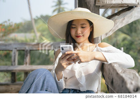 Happy asian girl playing with smartphone. 68184014