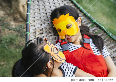 Two mask asian girls laying on a cot. Two mask asian girls laying on a cot. 68184266