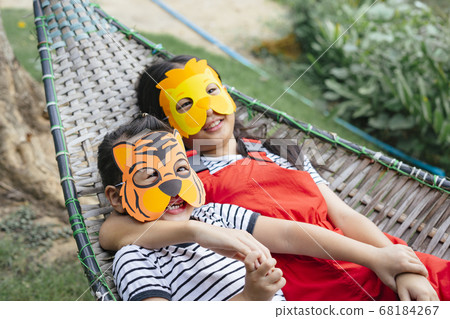 Two mask asian girls laying on a cot. Two mask asian girls laying on a cot. 68184267
