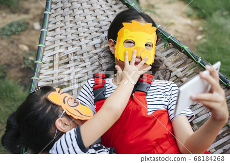 Two little asian girls wearing mask laying on a Two little asian girls wearing mask laying on a 68184268