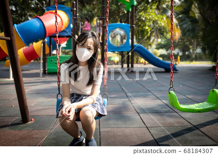Asian child girl wearing protective medical mask in playground,student girl with mask to prevent infection from Covid-19,Flu virus,Coronavirus,deserted playground caused by the outbreak of Covid-19 68184307