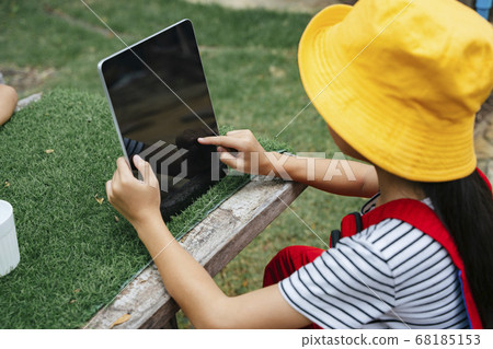 Girl playing tablet computer outdoors in nature. 68185153
