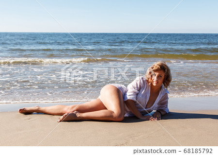 young woman in a white shirt lies on the sand of young woman in a white shirt lies on the sand of 68185792