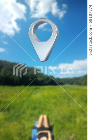 A person lies on a green meadow under a large way waypoints symbol 68187874