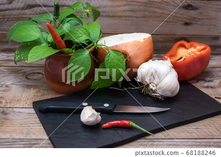 cooking ingredients and spices such as chili, garlic, onion and pepper on a blackboard to cut and prepare them for cooking cooking ingredients and spices such as chili, garlic, onion and pepper on a blackboard to cut and prepare them for cooking 68188246