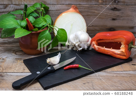 cooking ingredients and spices such as chili, garlic, onion and pepper on a blackboard to cut and prepare them for cooking 68188248