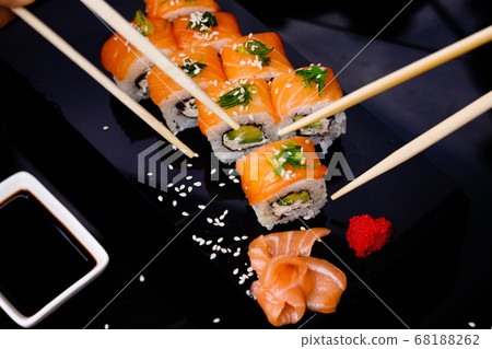 Sushi with salmon. Soy sauce, red caviar. Sushi on a black background. 68188262