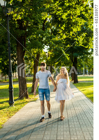 pregnant woman with her husband walking in a park 68188977