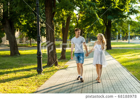 pregnant woman with her husband walking in a park 68188978