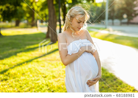Portrait of a happy pregnant woman in a park Portrait of a happy pregnant woman in a park 68188981