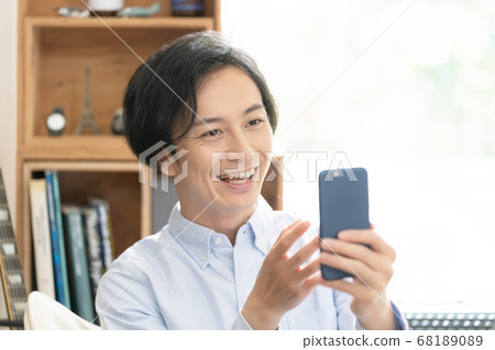 一名男子在智能手機上觀看視頻分發 一名男子在智能手機上觀看視頻分發 68189089