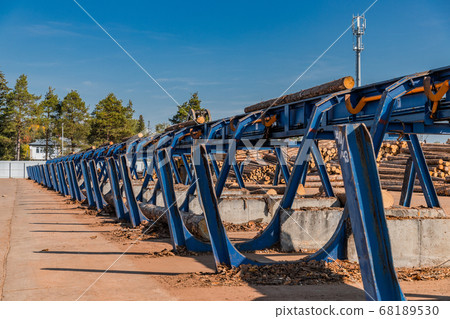 Automated log sorting line. Production of timber from wood. Woodworking. Machining logs. The logs in the sawmill are moving along a conveyor belt 68189530