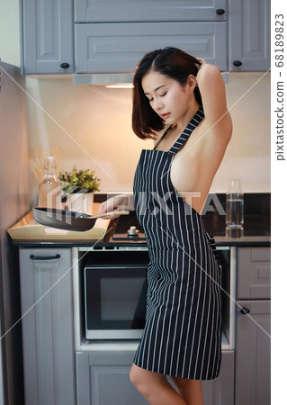 sexy and attractive asian woman wife in sexy apron cooking in kitchen with smiling face  68189823