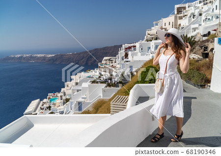 Europe Greece Santorini travel vacation woman on famous santorini Oia island travel destination. Happy young tourist woman. Summer wanderlust. Europe Greece Santorini travel vacation woman on famous santorini Oia island travel destination. Happy young tourist woman. Summer wanderlust. 68190346