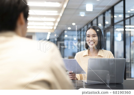 Young business person discussing work while looking at the PC through an acrylic plate for preventing splash infection Young business person discussing work while looking at the PC through an acrylic plate for preventing splash infection 68190360