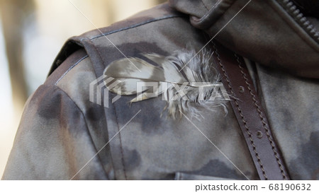 Bird feather stuck under belt on shoulder of hunter dressed in camouflage. Man in comfortable camouflage clothes hunter outdoor in forest hunting alone. 68190632