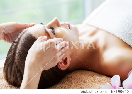 Young beautiful girl having face massage relaxing in spa salon. 68190640