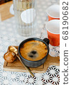 top view  hot black coffee in black ceramic cup on wooden tray put white table with red plastic cups and glass bottle of water on white table, copy space 68190682