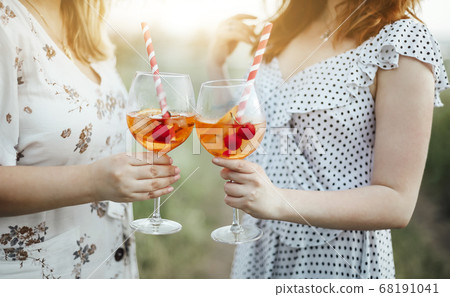 Two young women carrying goblet of alcohol Two young women carrying goblet of alcohol 68191041
