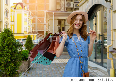 Young Woman with shopping bags walking in a city at summer day Young Woman with shopping bags walking in a city at summer day 68191199
