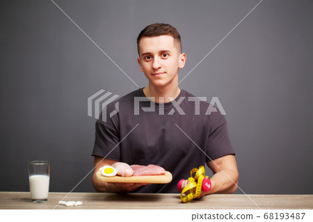 Shaped and healthy man holding a fresh meal board with meat 68193487