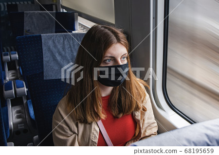 Young woman wearing protective face mask travelling by traing. 68195659
