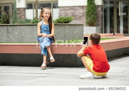 Two smiling kids, boy and girl taking photo together in town, city in summer day 68196032