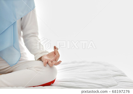 muslim woman sit on bed and enjoying meditation. Beautiful girl in sleepwear practices yoga on bed muslim woman sit on bed and enjoying meditation. Beautiful girl in sleepwear practices yoga on bed 68197276