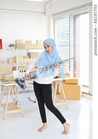 Happy young beautiful asian muslim housewife woman cleaning and playing vacuum cleaning like guitar Happy young beautiful asian muslim housewife woman cleaning and playing vacuum cleaning like guitar 68197793
