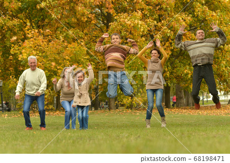 Happy smiling family relaxing in autumn park jumping Happy smiling family relaxing in autumn park jumping 68198471