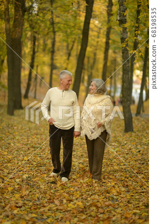 Happy senior woman and man in park walking Happy senior woman and man in park walking 68198535