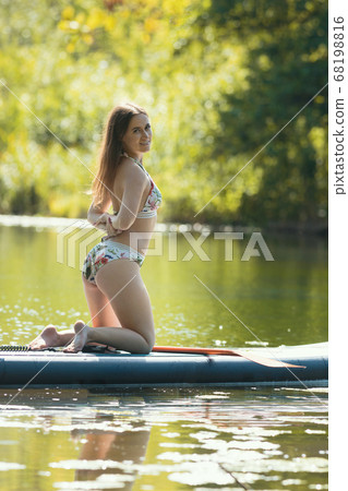 Young woman in floral swimsuit standing on her knees on the inflatable boat 68198816