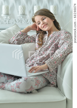 Portrait of cute girl using laptop on sofa Portrait of cute girl using laptop on sofa 68198874