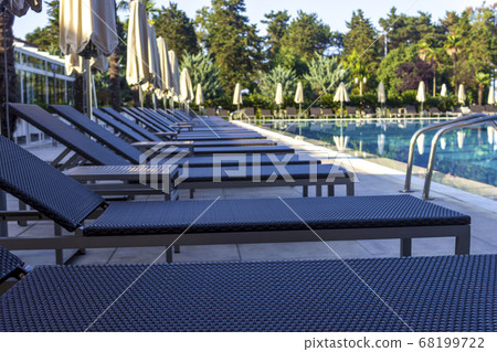Sun beds by the pool in the open air. Pool at the spa resort. 68199722