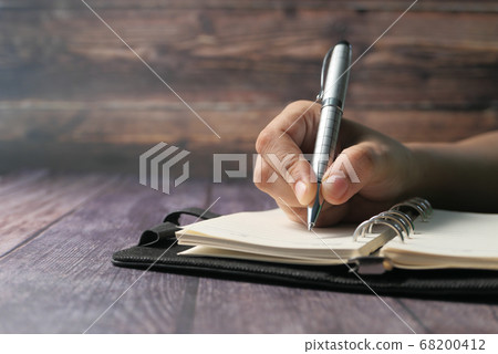 women hand writing with pen on notepad on table women hand writing with pen on notepad on table 68200412