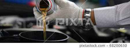 Close-up hands in gloves pour oil into car tank Close-up hands in gloves pour oil into car tank 68200630
