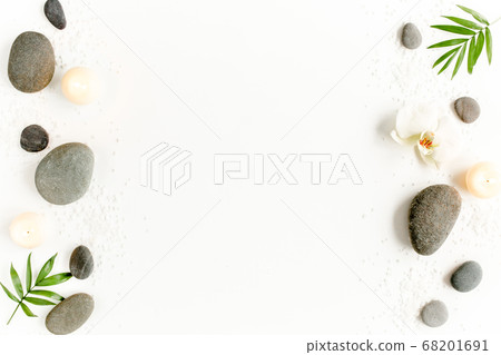 Spa stones, palm leaves, flower white orchid, candle and zen like grey stones on white background. Flat lay, top view 68201691