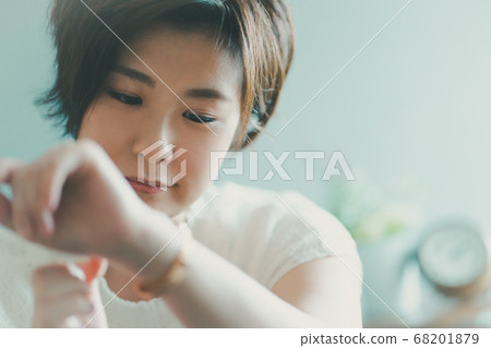 Woman in her 30s looking at a watch 68201879