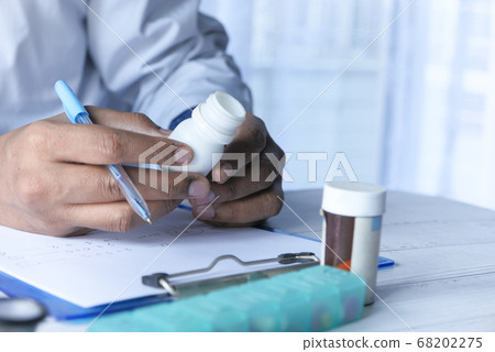Close up of doctor hand holding pill container. Close up of doctor hand holding pill container. 68202275