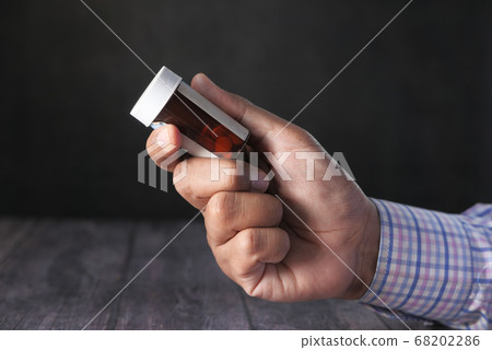 Close up of man hand holding pill container Close up of man hand holding pill container 68202286