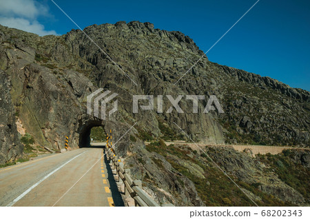 Road on rocky landscape passing through tunnel 68202343