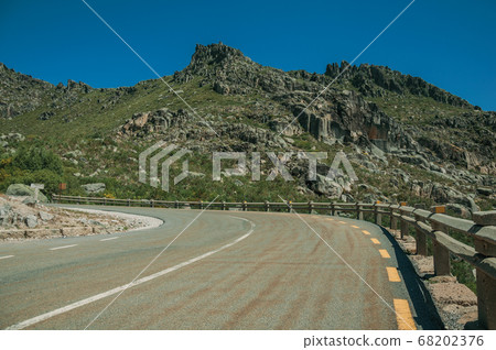 Curve roadway passing through rocky landscape Curve roadway passing through rocky landscape 68202376