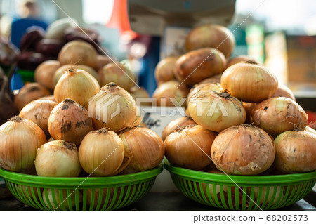 Bulbs of onion in green baskets. 68202573