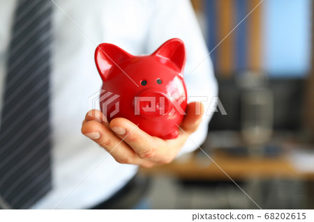 Male businessman hold in hand red little piggybank Male businessman hold in hand red little piggybank 68202615