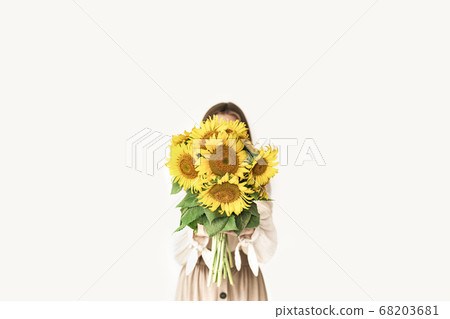 Beautiful young woman in linen dress holding sunflowers bouquet. 68203681