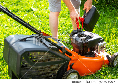 Man refueling the lawnmower on his huge garden, gardening concept 68203907