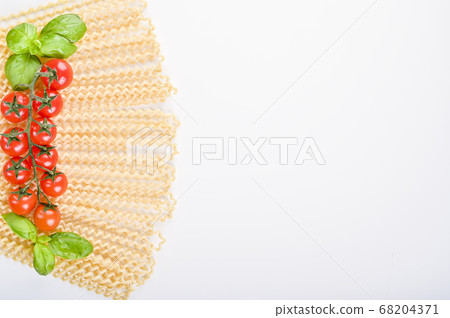 Fusilli lunghi bucati . Long curly pasta on a white plate, with fresh basil leaves and cherry Fusilli lunghi bucati . Long curly pasta on a white plate, with fresh basil leaves and cherry 68204371