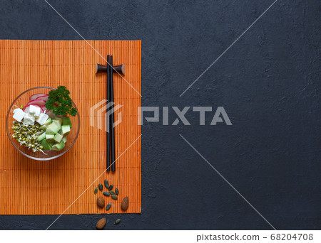 Appetizer of vegetable slices and mung bean sprouts with chopsticks, on a black background, top view with space 68204708