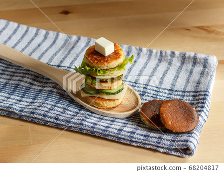 a delicious sandwich from the mini pancakes on a wooden spoon. on a checked towel, horizontally 68204817